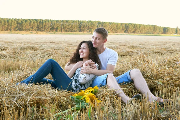 Felice giovane coppia siedono in campo di grano la sera, concetto di persone romantiche, bellissimo paesaggio, stagione estiva — Foto Stock