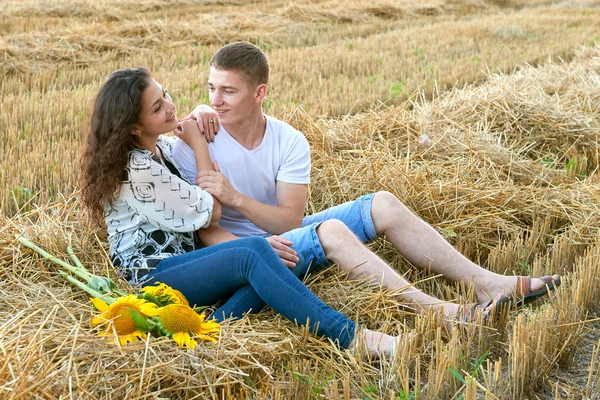 Feliz jovem casal sentar no campo de trigo à noite, conceito de pessoas românticas, bela paisagem, temporada de verão — Fotografia de Stock