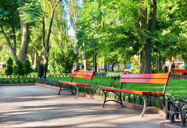 Zielonym parkiem miejskim, w sezonie letnim, jasnym świetle słonecznym i cienie, piękny krajobraz, domu i ludzi na ulicy — Zdjęcie stockowe