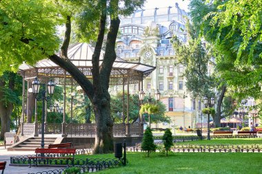 Merkezi şehir, yaz sezonu, parlak güneş ışığı ve gölgeler, güzel manzara, ev ve insanlar sokakta yeşil şehir parkında