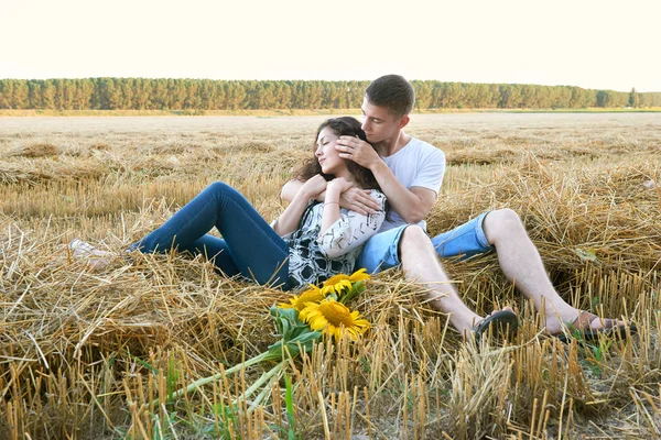 Feliz jovem casal sentar no campo de trigo à noite, conceito de pessoas românticas, bela paisagem, temporada de verão — Fotografia de Stock