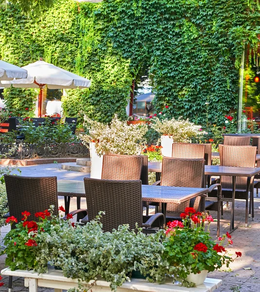 Caffè di strada estiva interno nel parco verde della città, decorato con fiori ed elementi decorativi, ombrello bianco — Foto Stock