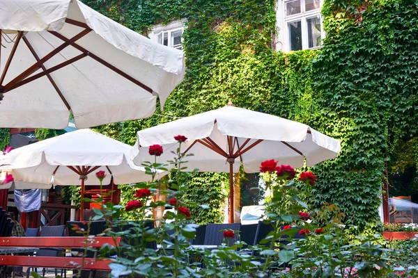 Summer street cafe interior in green city park, ornate with flowers and decorative elements, white umbrella — Stock Photo, Image