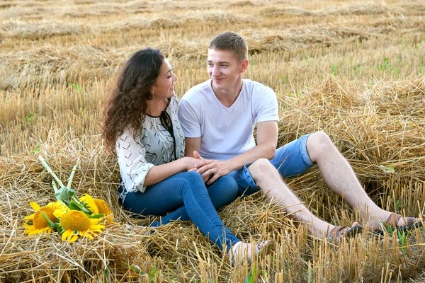 Feliz joven pareja sentarse en el campo de trigo por la noche, concepto de gente romántica, hermoso paisaje, temporada de verano — Foto de Stock