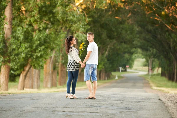 Задня частина молодої пари гуляє по сільській дорозі на відкритому повітрі, концепція романтичних людей, літній сезон — стокове фото