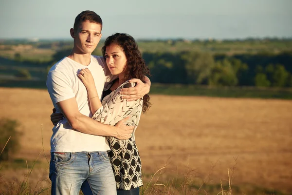 Jovem casal posando no fundo do campo de trigo, conceito romântico e ternura, temporada de verão — Fotografia de Stock