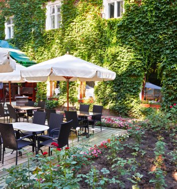 Yaz sokak kafe iç yeşil şehir Park, çiçekler ve dekoratif öğeler ile süslü beyaz şemsiye ile