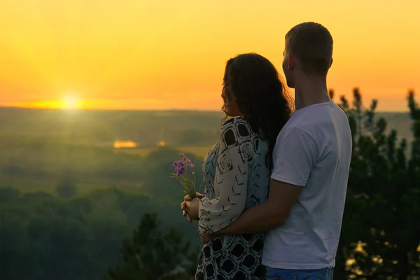 Romantyczna para patrzeć na słońce, wieczór na zewnątrz, piękny krajobraz i jasne niebo żółty, miłość koncepcja kruchość, młodych osób dorosłych — Zdjęcie stockowe