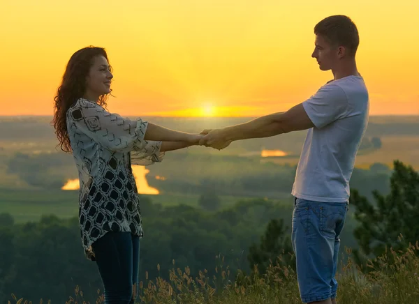 Romantische paar hand in hand bij zonsondergang op outdoor, prachtige landschap en helder gele hemel, liefde tederheid concept, volwassen jongeren — Stockfoto