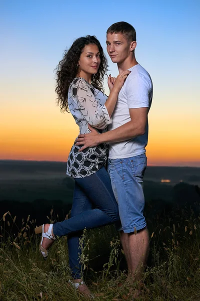 Romantisches Paar umarmt bei Sonnenuntergang, schöne Landschaft und strahlend gelben Himmel, Liebe Zärtlichkeit Konzept, junge erwachsene Menschen — Stockfoto