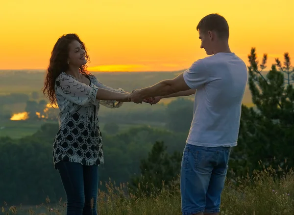 Романтична пара тримає руки на заході сонця на відкритому повітрі, красивий пейзаж і яскраво-жовте небо, любов концепція ніжності, молоді дорослі люди — стокове фото