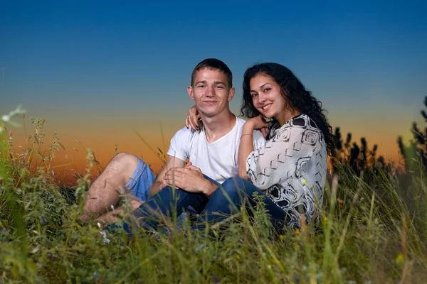 Романтична пара сидить на траві на заході сонця на відкритому повітрі, красивий пейзаж і темне нічне небо, концепція кохання ніжності, молоді дорослі люди — стокове фото