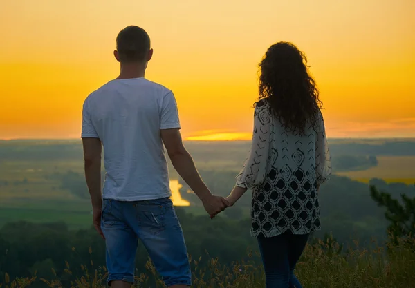 Couple romantique regardant au loin au coucher du soleil sur l'extérieur, beau paysage et ciel jaune vif, concept de tendresse d'amour, les jeunes adultes — Photo