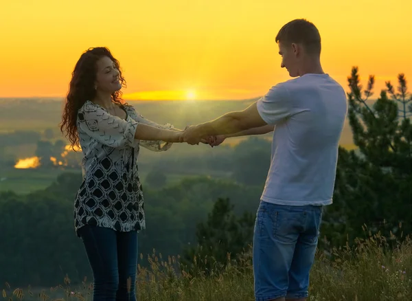 Romantisches Paar Händchenhalten bei Sonnenuntergang im Freien, schöne Landschaft und strahlend gelber Himmel, Liebe Zärtlichkeit Konzept, junge erwachsene Menschen — Stockfoto