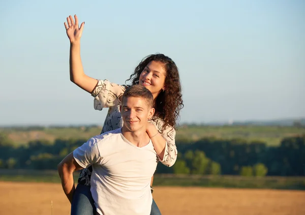 happy young couple walk on country outdoor, romantic people concept, summer season, girl riding on man back and waving