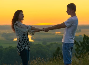 gökyüzü, aşk hassasiyet kavramı, genç yetişkin insanlar elele açık, güzel manzara ve parlak gün batımında romantik çift sarı