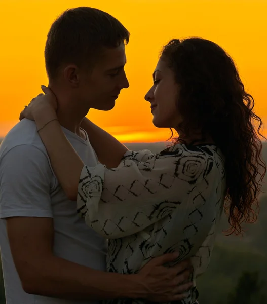 Couple romantique embrasser au coucher du soleil sur l'extérieur, beau paysage et ciel jaune vif, concept de tendresse amour, les jeunes adultes — Photo