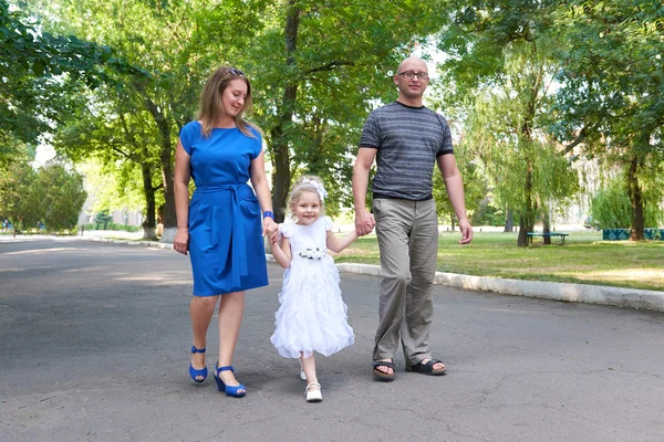 Šťastná rodina chodí v městském parku, rodiče s dítětem, letní sezóna, zelenou trávu a stromy — Stock fotografie