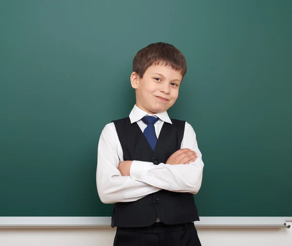 Studente ragazzo della scuola in posa alla lavagna pulita, smorfia ed emozioni, vestito in un abito nero, concetto di educazione, foto di studio — Foto Stock