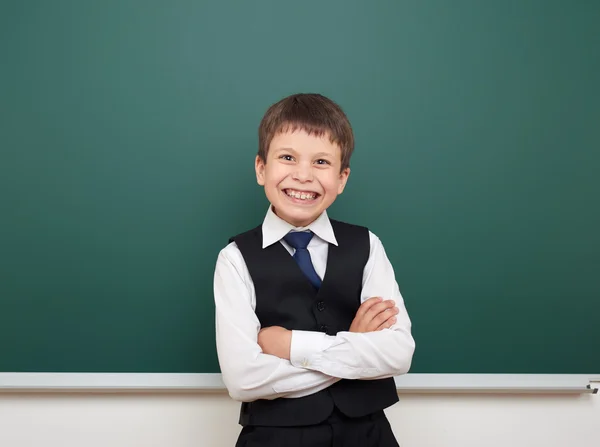 School student boy posing at the clean blackboard, grimacing and emotions, dressed in a black suit, education concept, studio photo — Stock Photo, Image