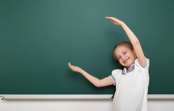 School student girl open arms at the clean blackboard, grimacing and emotions, dressed in a black suit, education concept, studio photo — Stock Photo, Image