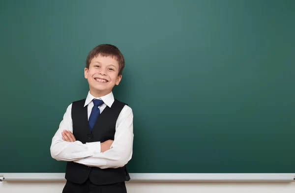 School student boy posing at the clean blackboard, grimacing and emotions, dressed in a black suit, education concept, studio photo — Stock Photo, Image