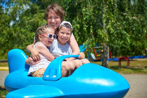 Niño y mujer vuelan en la atracción del avión azul en el parque de la ciudad, familia feliz, concepto de vacaciones de verano —  Fotos de Stock