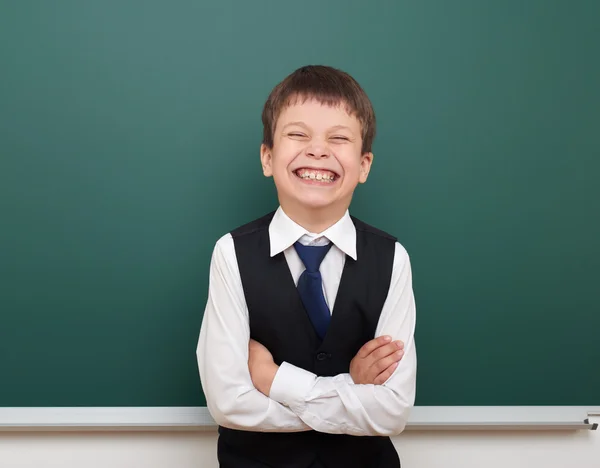 School student boy posing at the clean blackboard, grimacing and emotions, dressed in a black suit, education concept, studio photo — Stock Photo, Image