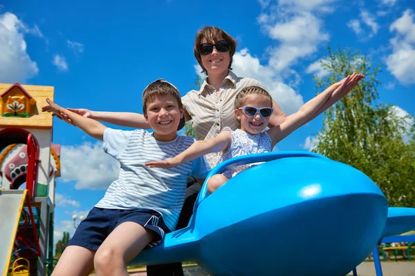 Niño y mujer vuelan en la atracción azul del avión en el parque de la ciudad, familia feliz, concepto de vacaciones de verano —  Fotos de Stock