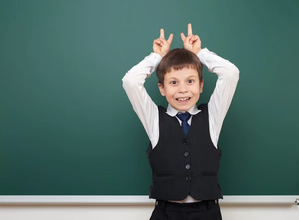 Schüler posiert an der sauberen Tafel, Grimassen und Emotionen, im schwarzen Anzug, Ausbildungskonzept, Studiofoto — Stockfoto