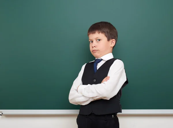 School student jongen die zich voordeed op de schone blackboard, grimassen en emoties, gekleed in een zwart pak, onderwijs concept, studio foto — Stockfoto