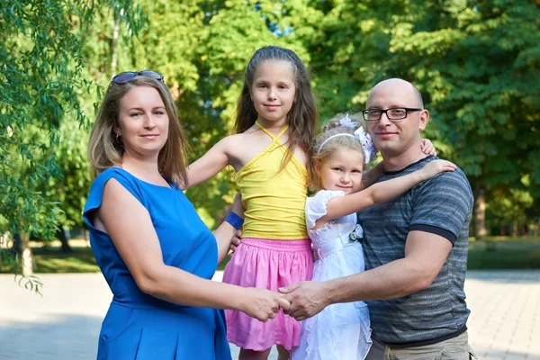 Šťastná rodina pózuje na venkovní, skupina čtyři lidi portrétu v městském parku, letní sezóny, dítě a rodič — Stock fotografie