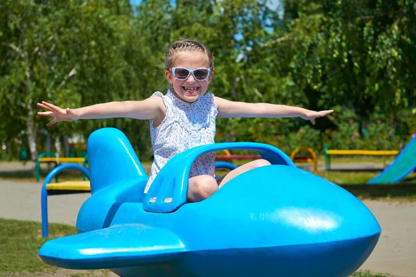 Niña volar en la atracción plano azul en el parque de la ciudad, la infancia feliz, el concepto de vacaciones de verano — Foto de Stock