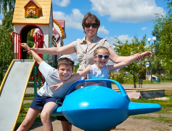 Niño y mujer vuelan en la atracción del avión azul en el parque de la ciudad, familia feliz, concepto de vacaciones de verano —  Fotos de Stock