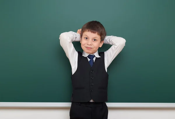 School student jongen die zich voordeed op de schone blackboard, grimassen en emoties, gekleed in een zwart pak, onderwijs concept, studio foto — Stockfoto