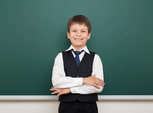 School student boy posing at the clean blackboard, grimacing and emotions, dressed in a black suit, education concept, studio photo — Stock Photo, Image