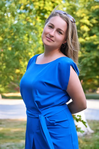 Schöne Frau im blauen Kleid posiert im Stadtpark — Stockfoto