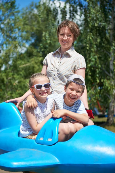 Niño y mujer vuelan en la atracción azul del avión en el parque de la ciudad, familia feliz, concepto de vacaciones de verano —  Fotos de Stock