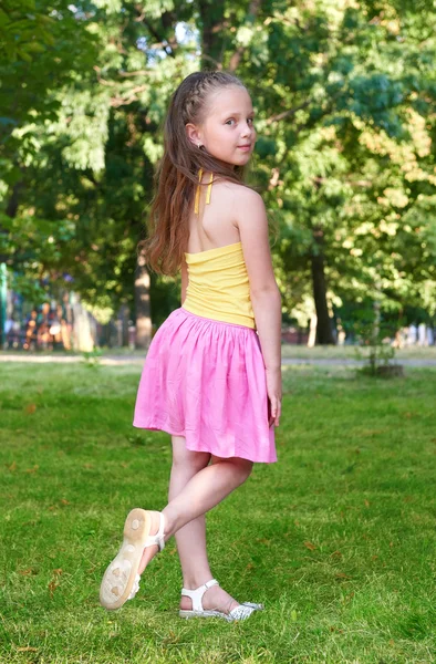 Felice bambina vestita in tessuto casual posa, concetto di infanzia, stagione estiva nel parco della città — Foto Stock