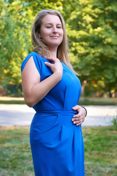 Beautiful woman in blue gown posing in city park — Stock Photo, Image