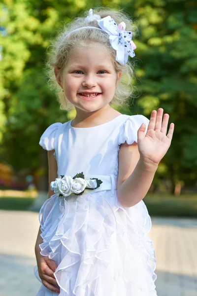 Barn tjej porträtt, poserar i vit klänning, lycklig barndom koncept, sommarsäsongen i stadsparken — Stockfoto