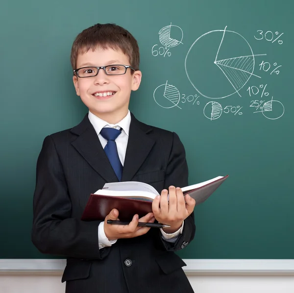 Школьник с книжным портретом, круговая диаграмма с процентами рисунков на доске, одетый в классический черный костюм, концепция образования — стоковое фото