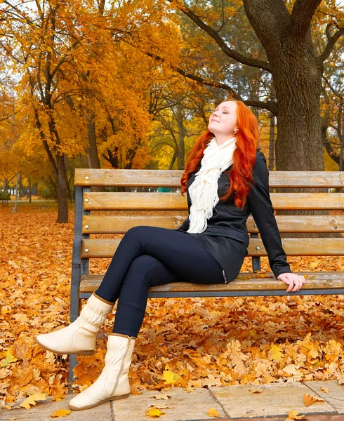 아름다운 어린 소녀 초상화공원에서 벤치에 앉아 휴식을 취하고, 가을 시즌에 노란색 잎, 빨간 머리, 긴 머리 — 스톡 사진