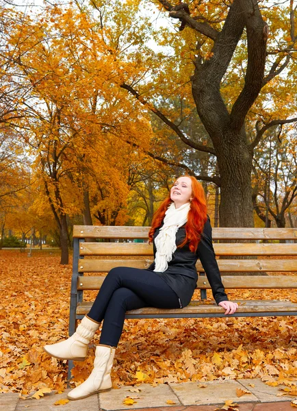 Bela jovem retrato sentar no banco no parque e relaxar, folhas amarelas na temporada de outono, ruiva, cabelos longos — Fotografia de Stock