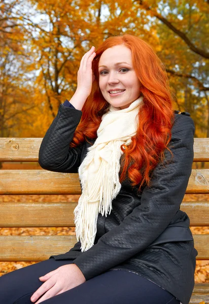Krásná mladá dívka portrét sedí na lavičce v parku, žluté listí na podzim, zrní, dlouhé vlasy — Stock fotografie