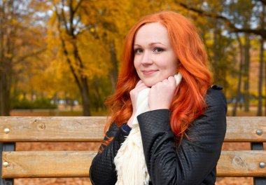 güzel genç kız portre parkta bankta oturup, sonbahar sezonunda sarı yaprakları, kızıl saçlı, uzun saçlı