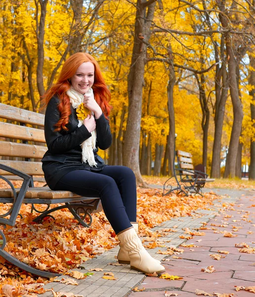 Beautiful young girl portrait sit on bench in park with yellow leaf in hand, fall season, redhead, long hair — Stock Photo, Image