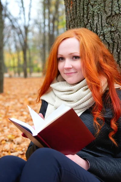 Girl with book sit on yellow leaves in autumn forest — Stock Photo, Image