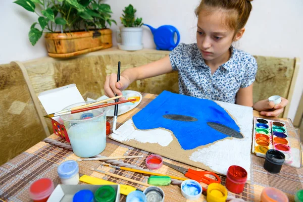 青いガッシュの段ボールを描く少女は家で創造的なアートワークを作り — ストック写真