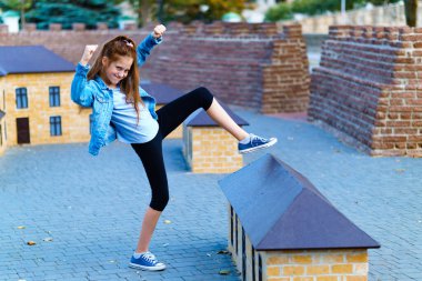 Kız şehir parkında minyatür evlerle oynuyor.